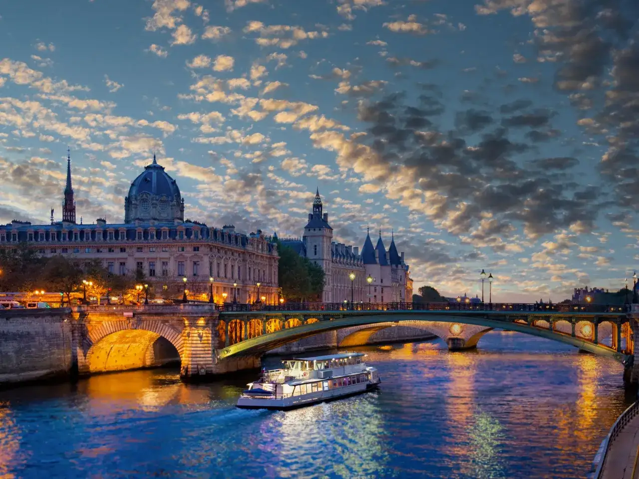 Rejs po Sekwanie w Paryżu. Zastanawiasz się, ile euro na tydzień do Francji? Widok na zamek Conciergerie i most Pont Neuf o zmierzchu.