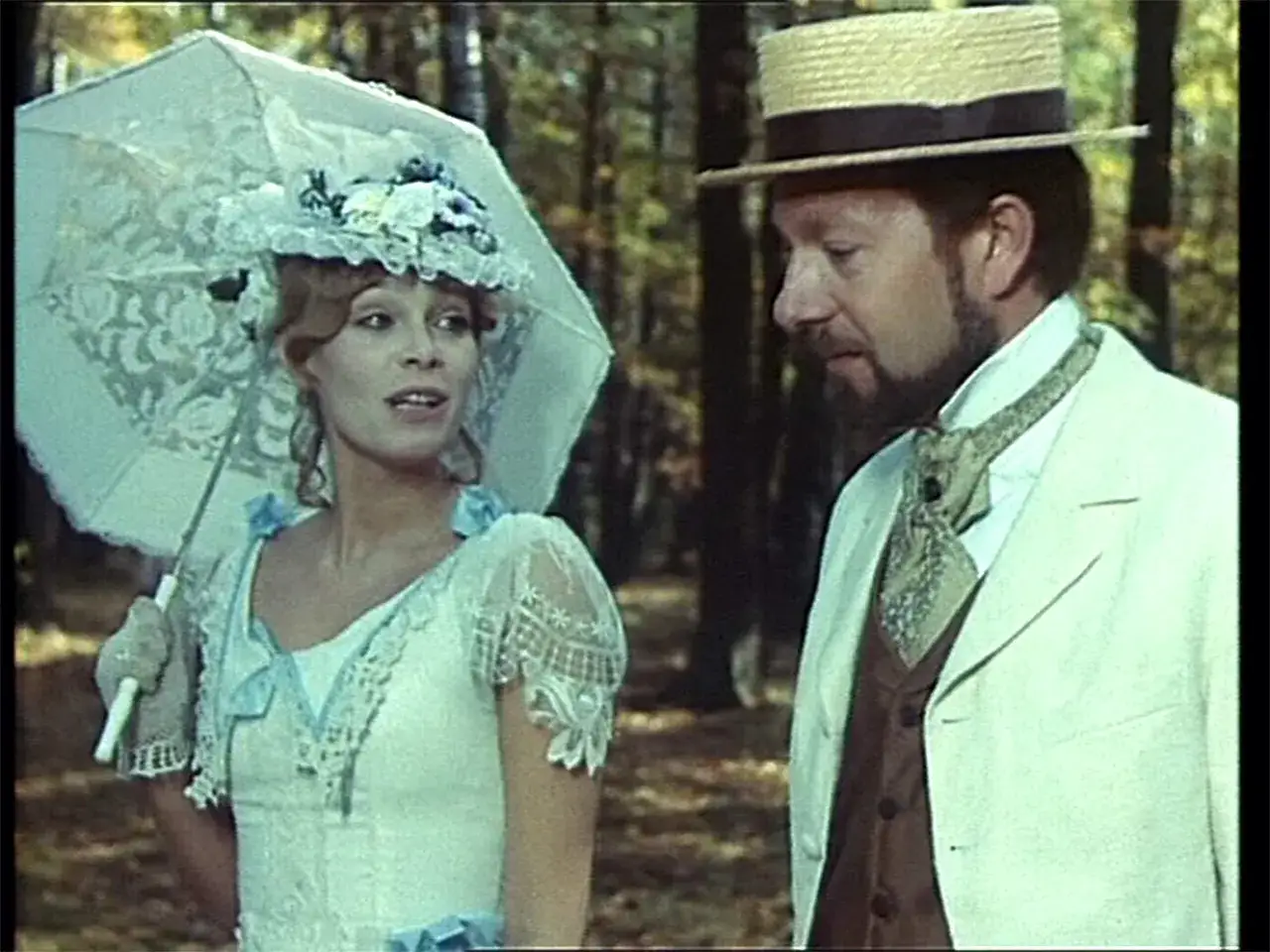 Kobieta w białej sukni i kapeluszu z woalką, z parasolką w ręku, rozmawia z mężczyzną w słomkowym kapeluszu. Scena jak z filmu 