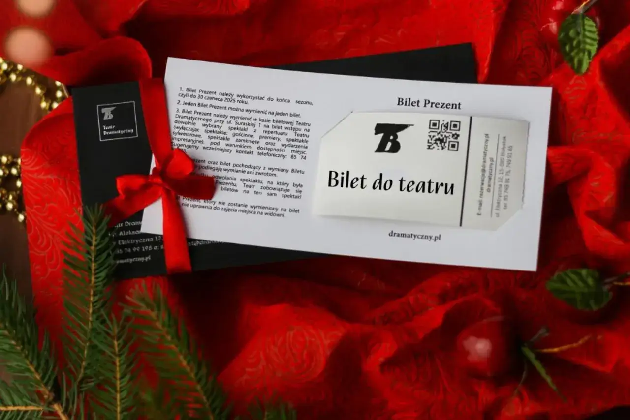 Elegancki prezent urodzinowy: bilet do teatru. Czerwona wstążka i świąteczne ozdoby podkreślają wyjątkowość tego spektaklu.