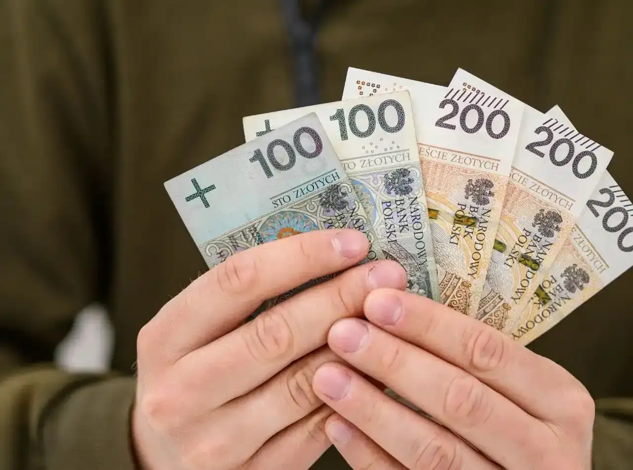 Dłonie trzymają polskie banknoty 100 i 200 zł. To może być kwota, kt&oacute;ra pokryje maksymalną prowizję za udzielenie pożyczki.