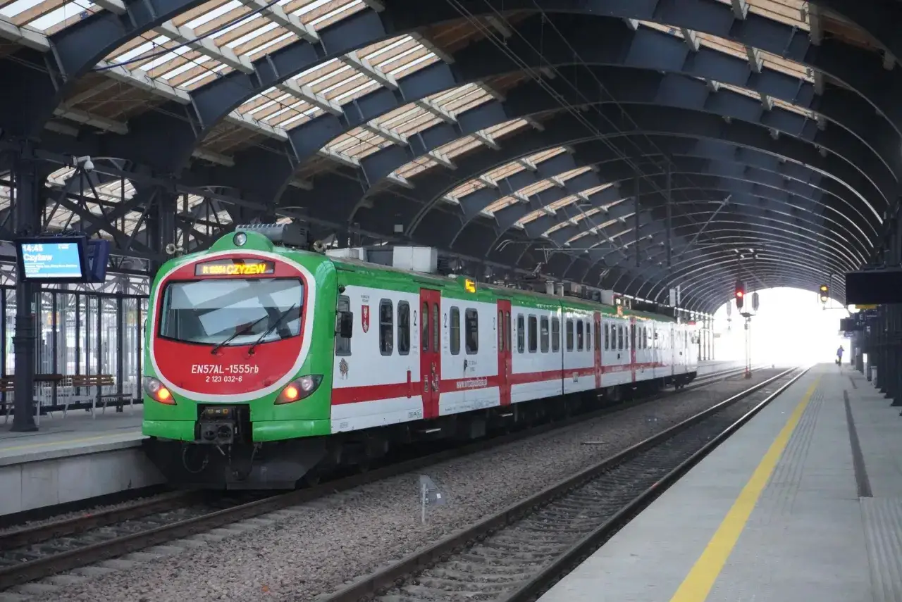 Zielono-czerwony pociąg EN57AL na stacji, gotowy do odjazdu. Może to być dzień, kiedy jest zmiana rozkładu jazdy PKP.