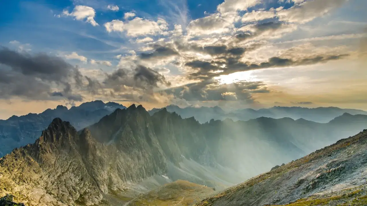 Majestatyczne szczyty Tatr Słowackich, od kiedy otwarte szlaki w tatrach słowackich, skąpane w promieniach słońca przebijających się przez chmury.