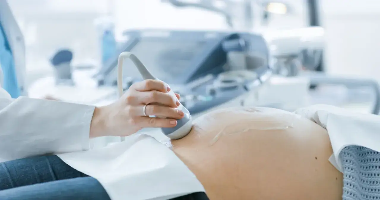 Pierwsze badanie prenatalne: lekarz wykonuje USG brzucha ciężarnej. Dowiedz się, jak przygotować się do tego ważnego badania.