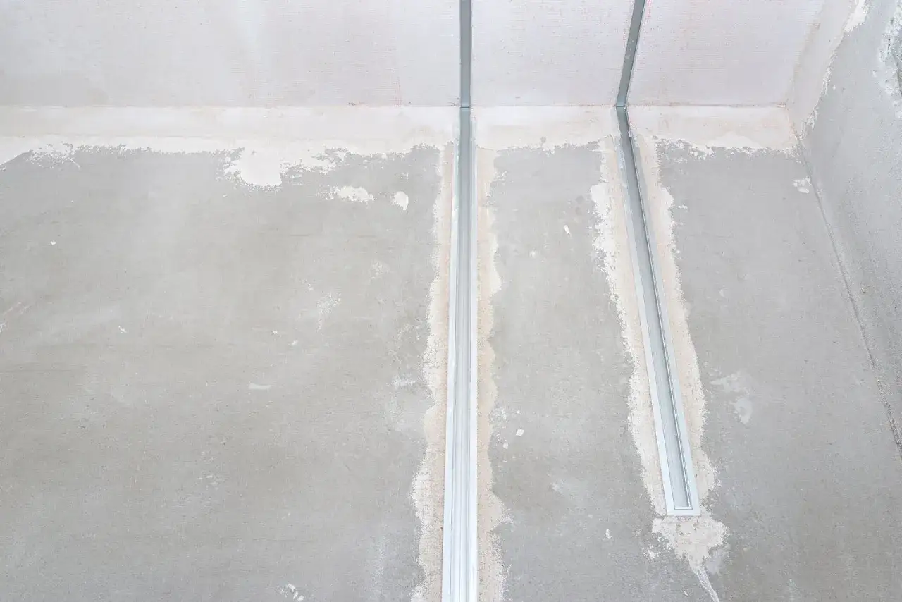 Dwa długie profile aluminiowe do led wpuszczone w sufit, przygotowane do montażu oświetlenia.