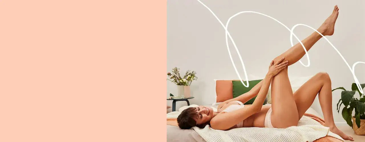 Kobieta leży na łóżku, przygotowując skórę do depilacji depilatorem. Gładkie nogi i uśmiech świadczą o komforcie.