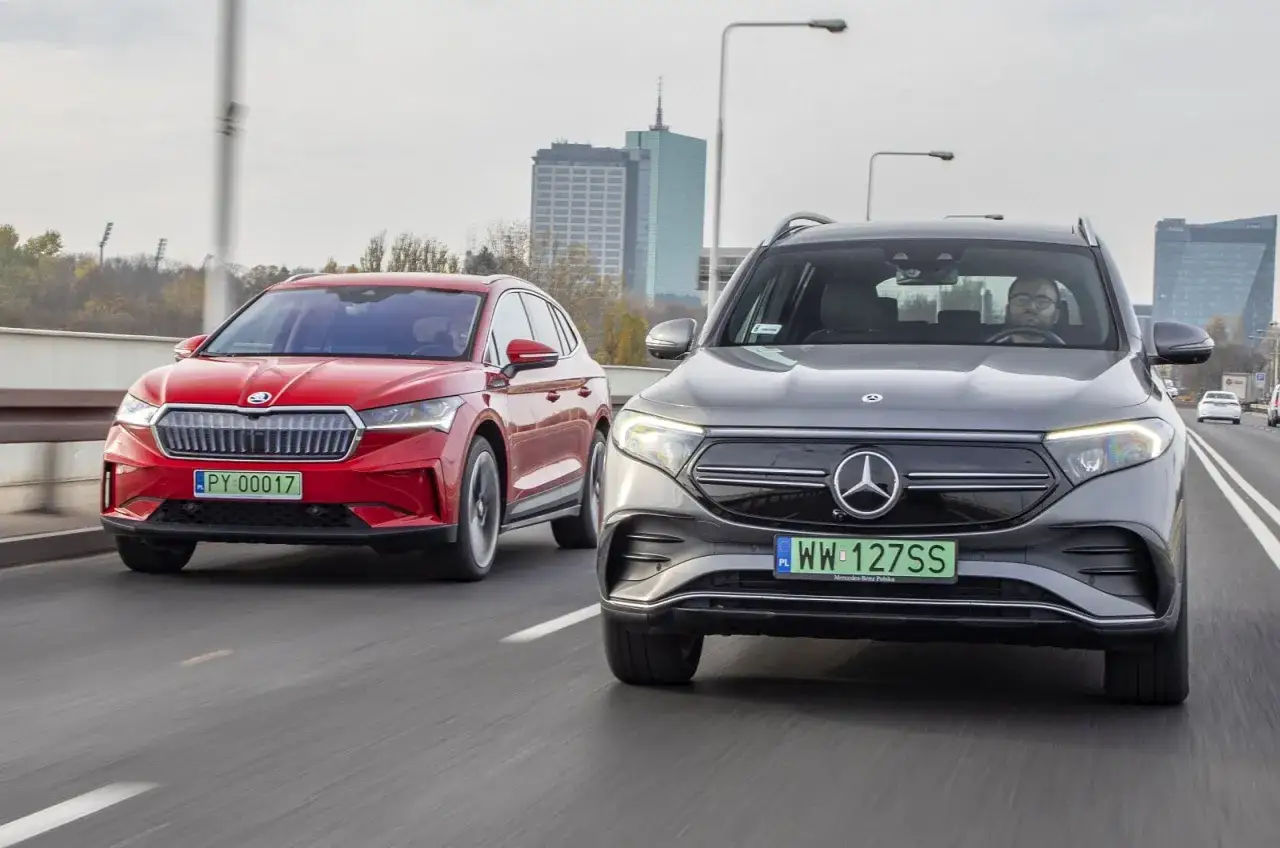 Szary Mercedes EQC z napędem 4matic i czerwona Skoda Enyaq jadą obok siebie po drodze.