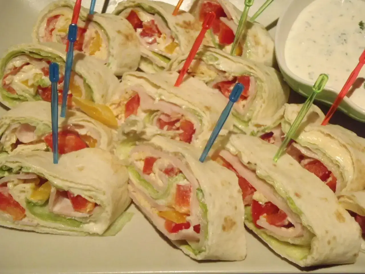 Pyszne przekąski z tortilli z warzywami i szynką, nadziane kolorowymi wykałaczkami. Idealne na imprezę!