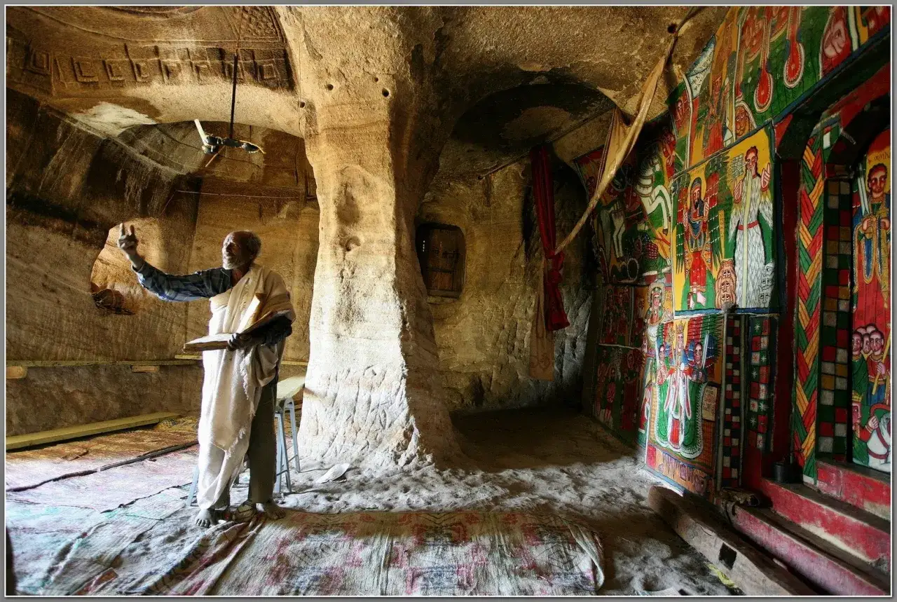 Etiopia wycieczka: starzec z księgą w skalnej cerkwi, ozdobionej barwnymi malowidłami.