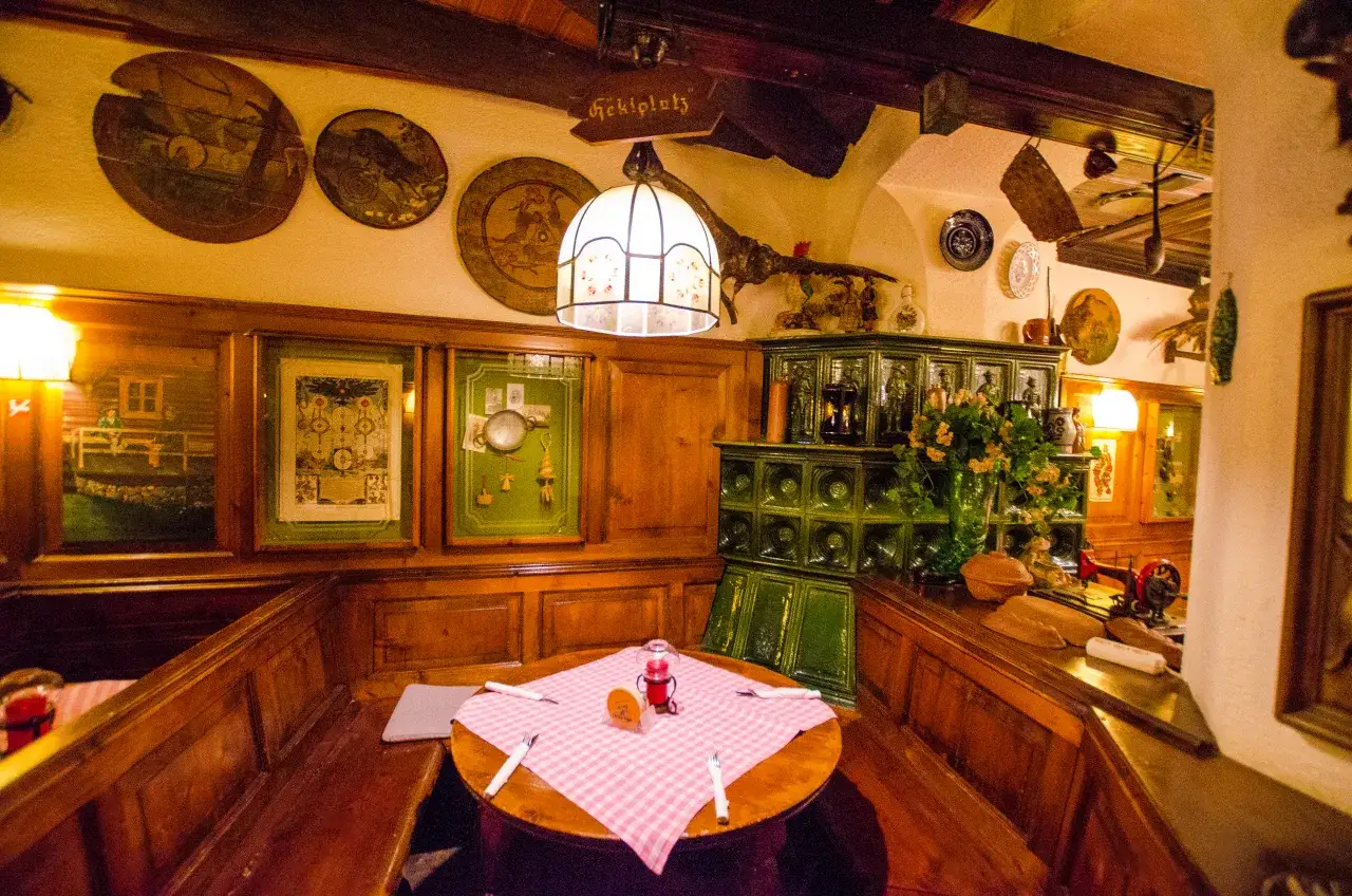 Przytulne wnętrze restauracji w Wiedniu, gdzie warto zjeść tradycyjne dania. Drewniane ławy, ozdobny piec i dekoracje tworzą wyjątkowy klimat.