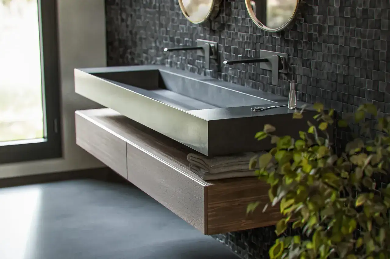 Nowoczesna łazienka z minimalistyczną umywalką z betonu, wiszącą szafką i czarną, mozaikową ścianą.