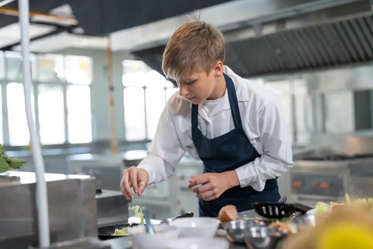 Młody kucharz doprawia danie na patelni. Nawet po zawodówce można iść do liceum, by rozwijać swoje pasje.