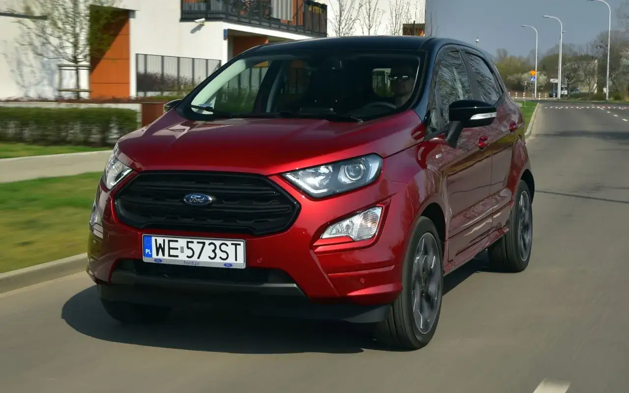 Czerwony Ford Ecosport z czarnym dachem jedzie po drodze.