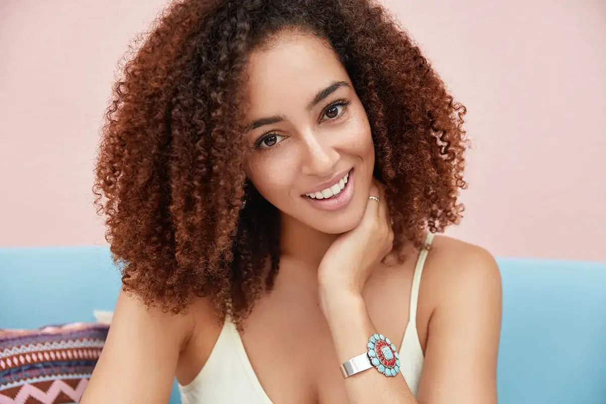 Uśmiechnięta kobieta z kręconymi włosami, idealne zdjęcie na portal randkowy.