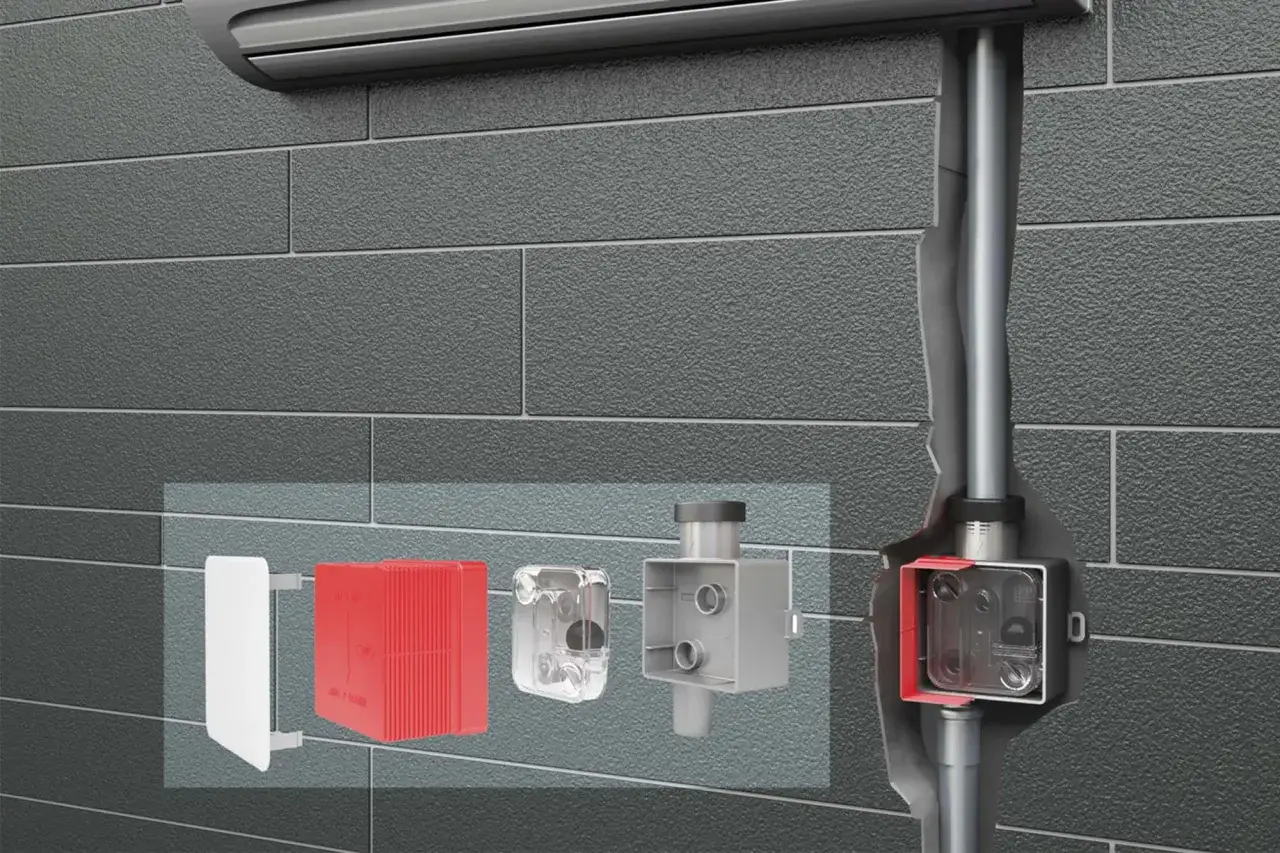 System odprowadzania skroplin z komina. Widoczne elementy: biała osłona, czerwony radiator, przezroczysty moduł, szara skrzynka z króćcami i pionowy pion.