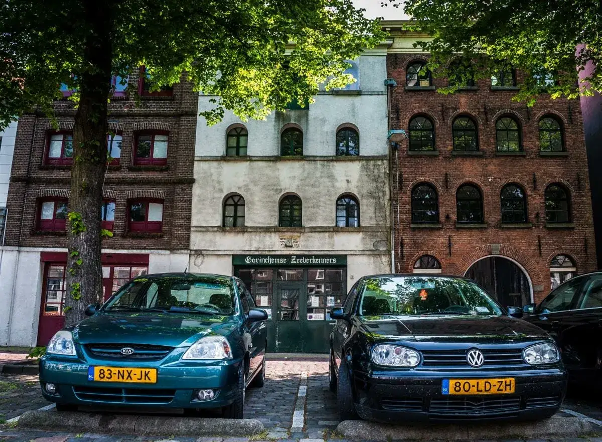 Dwa samochody zaparkowane przed budynkiem w Holandii. Zastanawiasz się, ile kosztuje sprowadzenie auta z Holandii?
