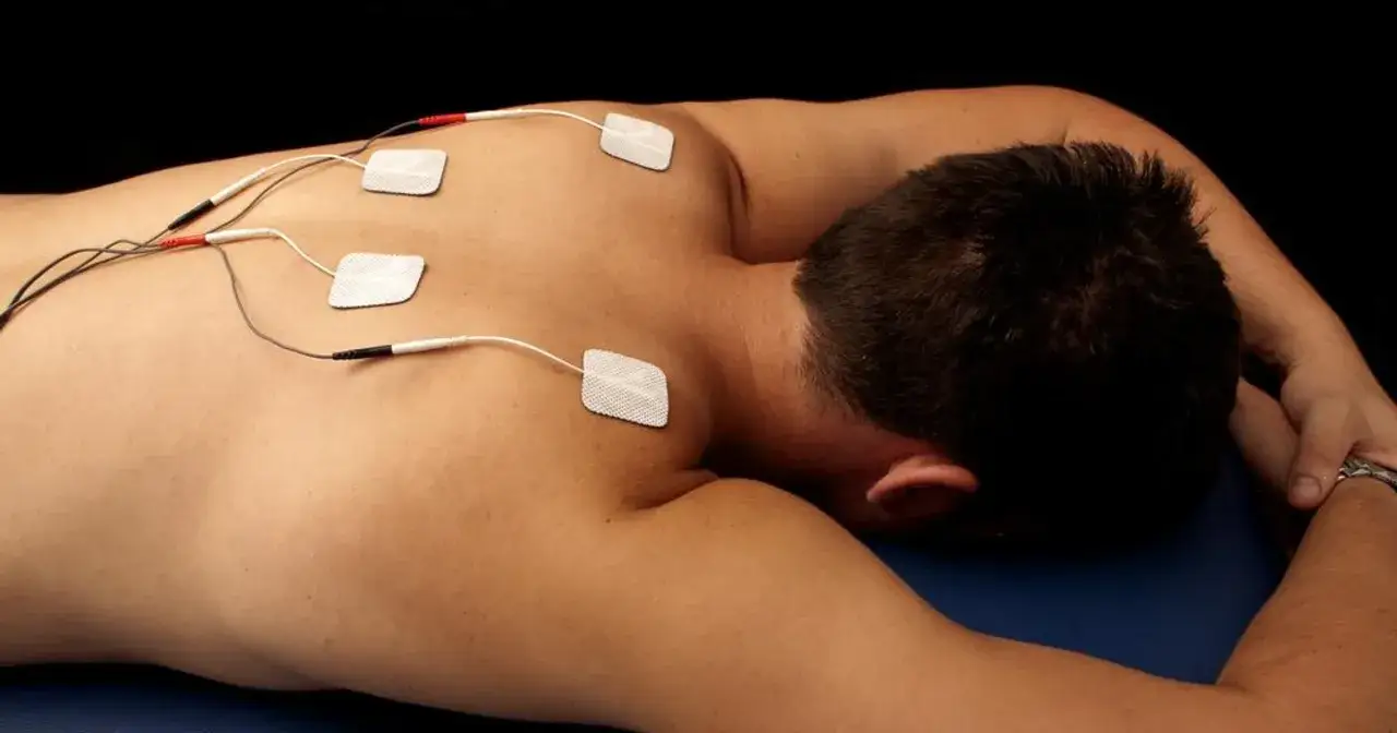 Rehabilitacja TENS: elektrody na plecach pacjenta. Ta metoda polega na stymulacji nerw&oacute;w prądem.