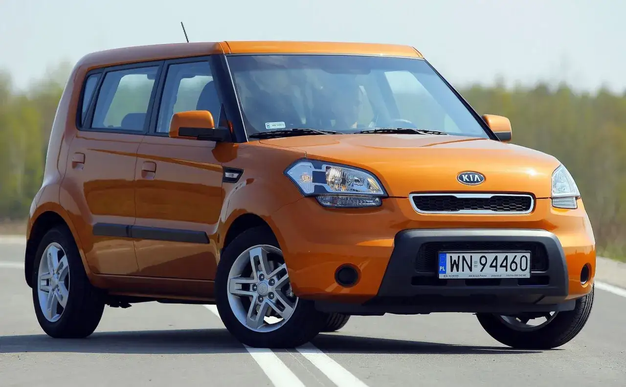 Pomarańczowy Kia Soul z polskimi tablicami rejestracyjnymi WN 94460 jedzie po drodze.