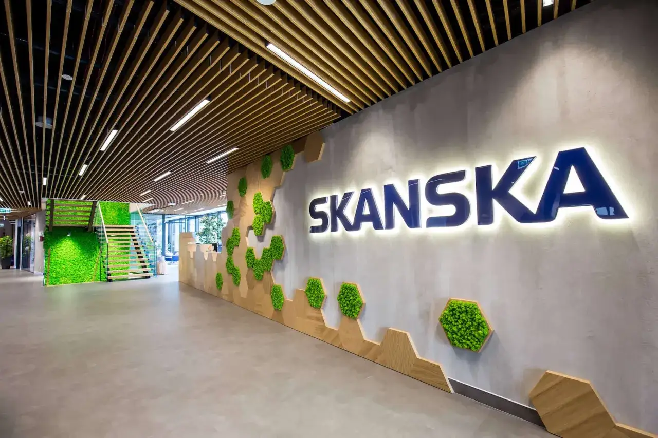 Nowoczesne wejście do obiektu Skanska z zielonymi panelami i drewnianymi elementami.