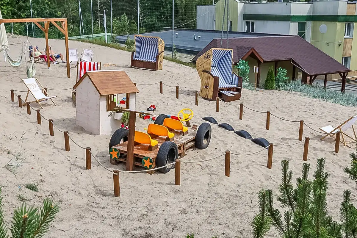 Piaskownica z zabawkami i pojazdami, idealne atrakcje dla dzieci Ustka. Leżaki i domki zachęcają do zabawy.