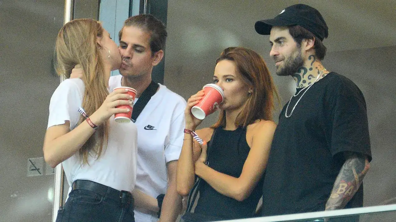 Para, czy Taco Hemingway jest w związku? Para całuje się, podczas gdy inni piją z kubków.