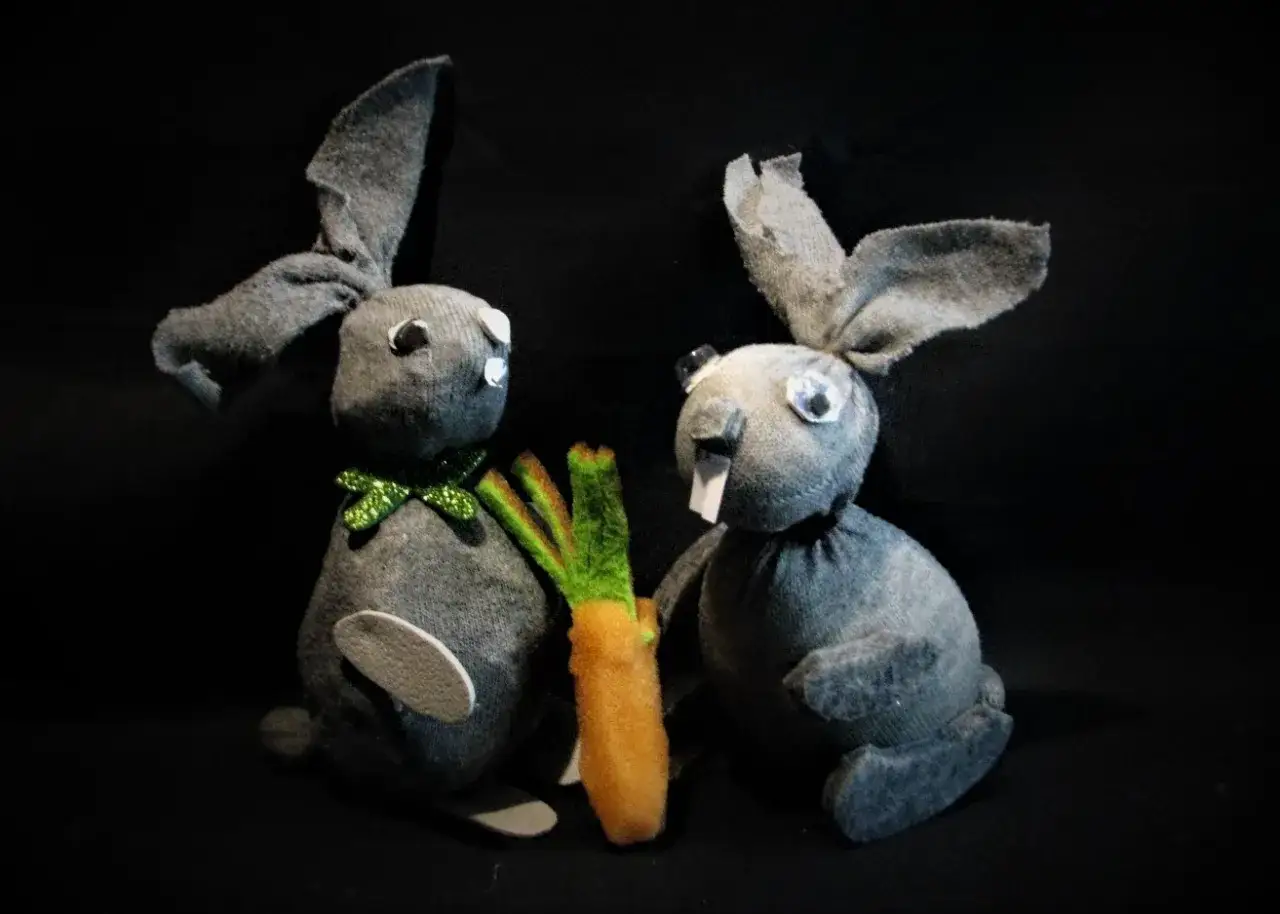 Dwa urocze króliczki z szarych skarpetek, jeden z zieloną kokardką, dzielą się marchewką. Oto co można zrobić ze skarpetek!