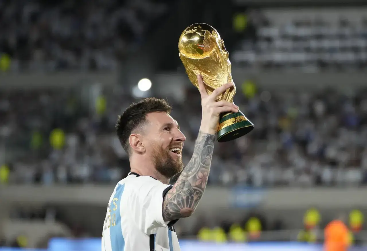 Lionel Messi, najbardziej utytułowany piłkarz w historii, triumfalnie unosi Puchar Świata.