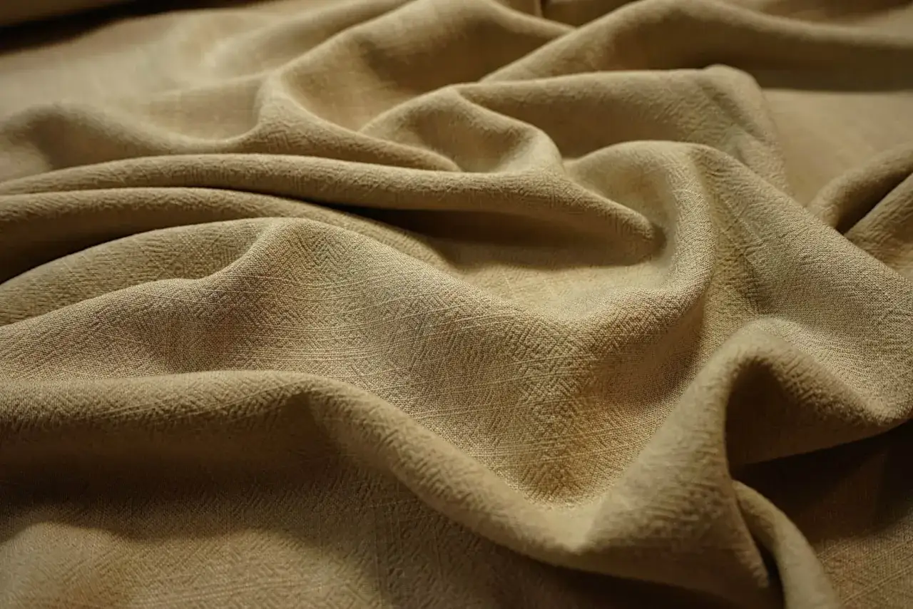 Beżowy, lekko pofałdowany materiał o subtelnym wzorze, idealny jako materiał na lato.