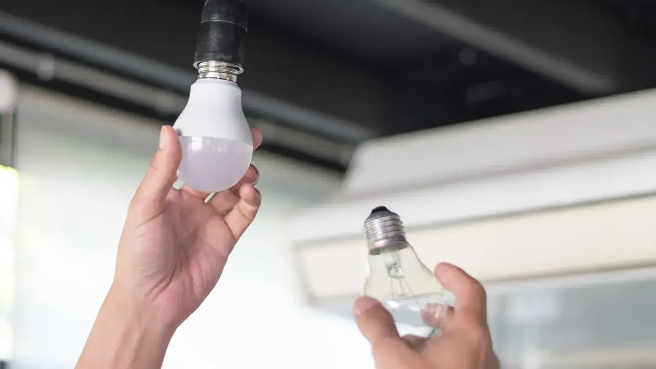 Ręce wymieniają starą żarówkę na nową LED. Prosty poradnik, jak wymienić żarówkę LED, by cieszyć się lepszym światłem.