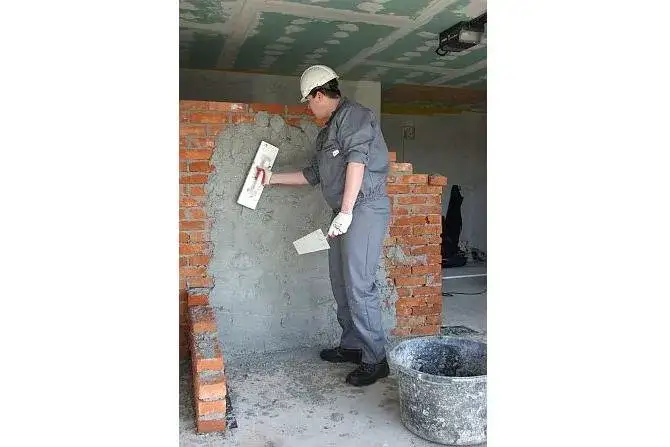 Tynkowanie ścian w domu, robotnik tynkuje ścianę