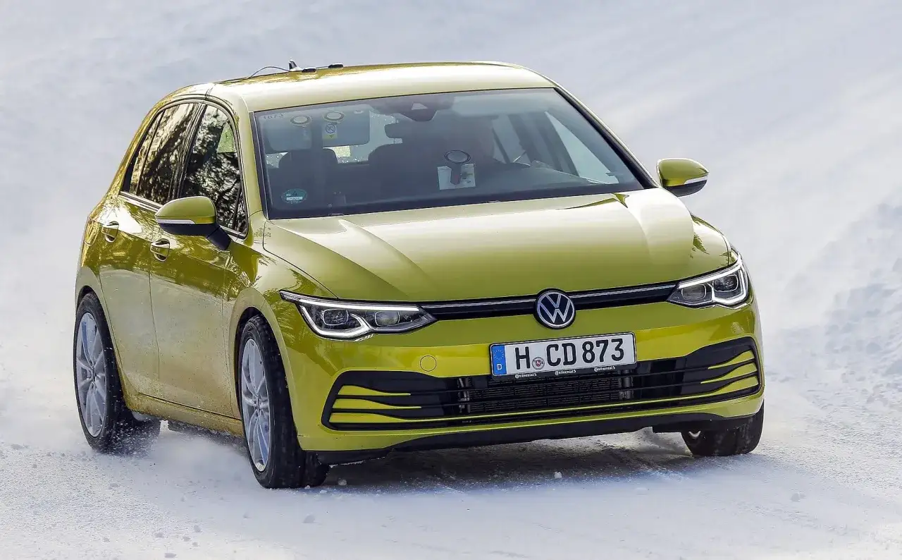 Żółty Volkswagen Golf na śniegu. Kierowca testuje, jakie opony zimowe wybrać, by bezpiecznie jeździć w trudnych warunkach.