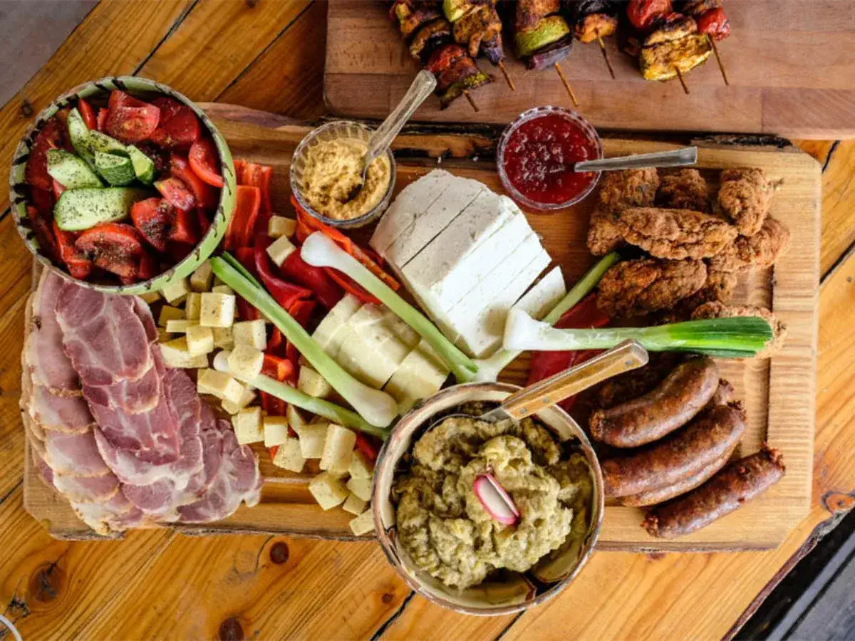 Obfity st&oacute;ł z tradycyjnym jedzeniem w Rumunii: wędliny, sery, kiełbaski, sałatka, dip i szaszłyki.