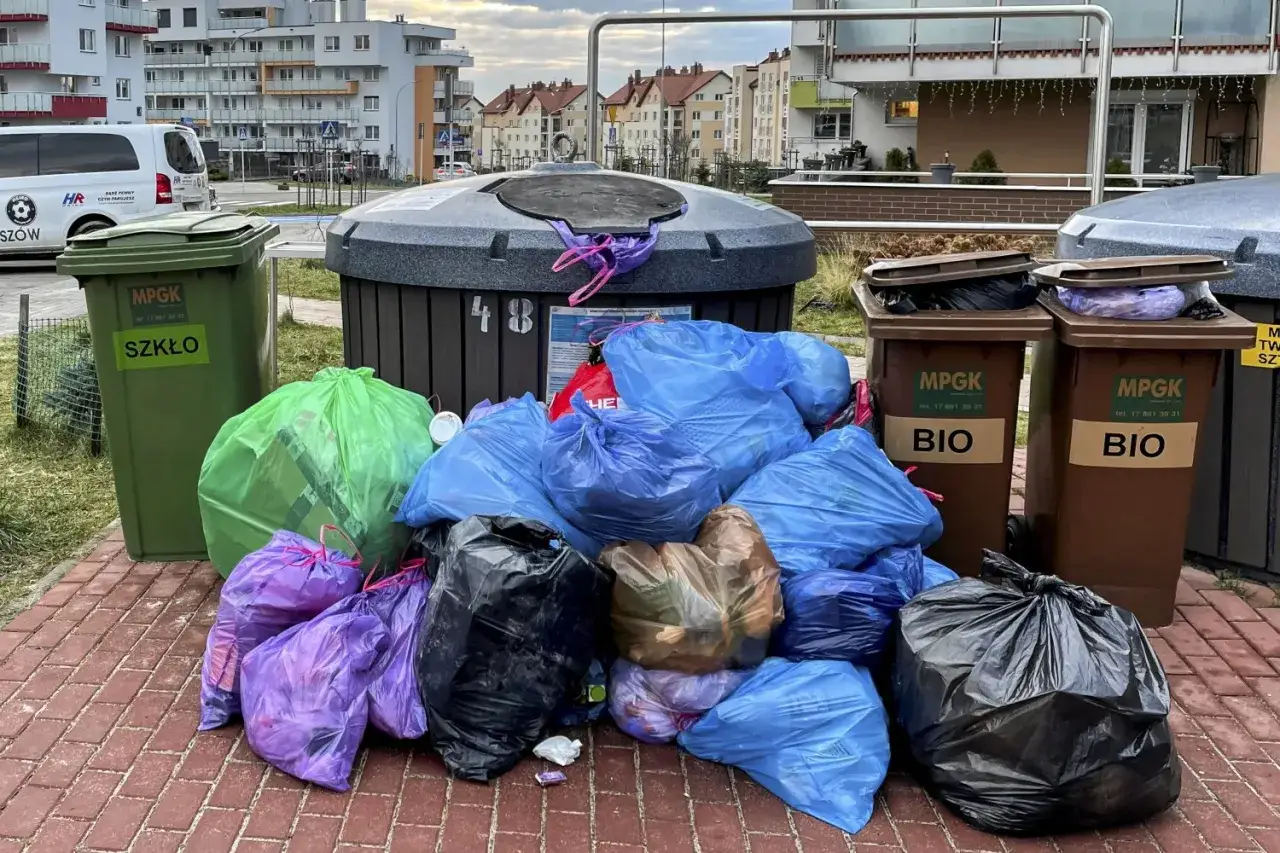 Gdzie wyrzucić stare ubrania? Stosy worków z odpadami przy kontenerach, w tym zielonym na szkło i brązowych na bio.