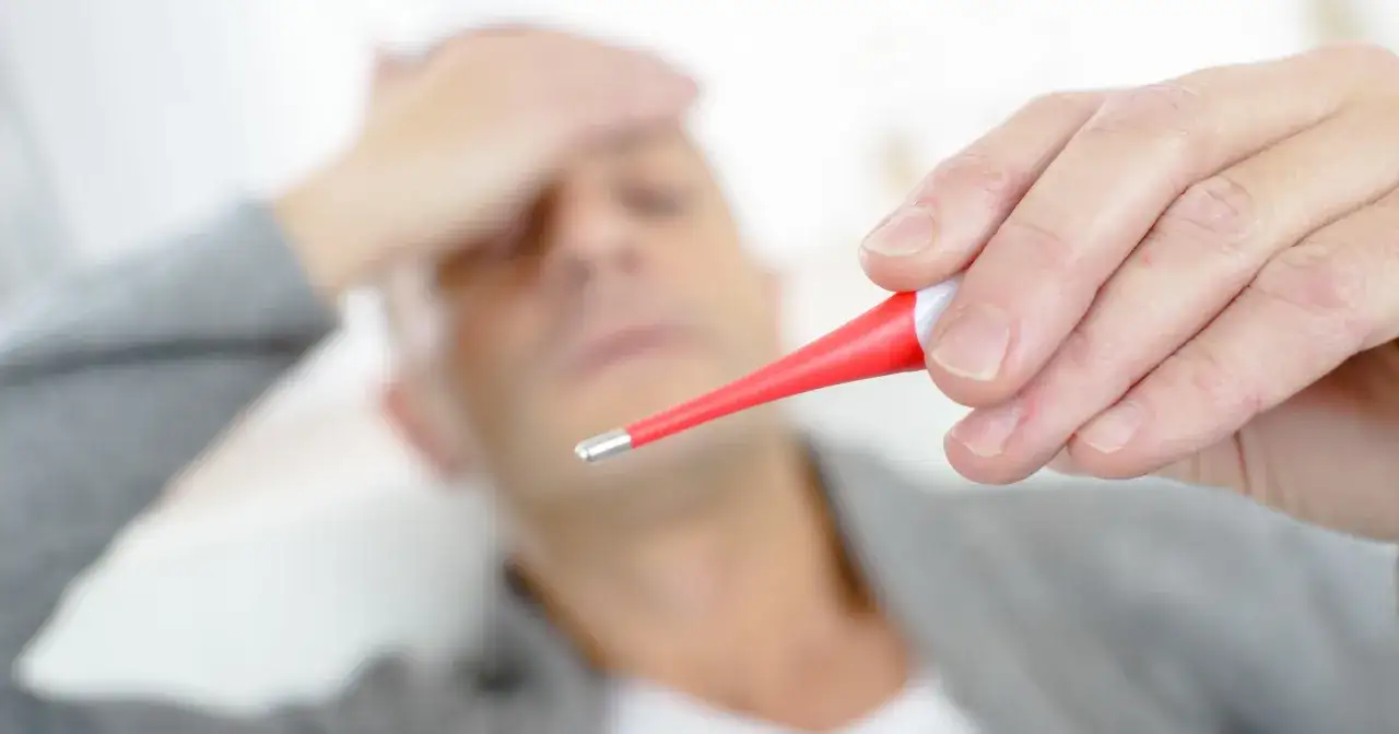 Osoba mierząca gorączkę i zastanawiająca się nad testem na COVID