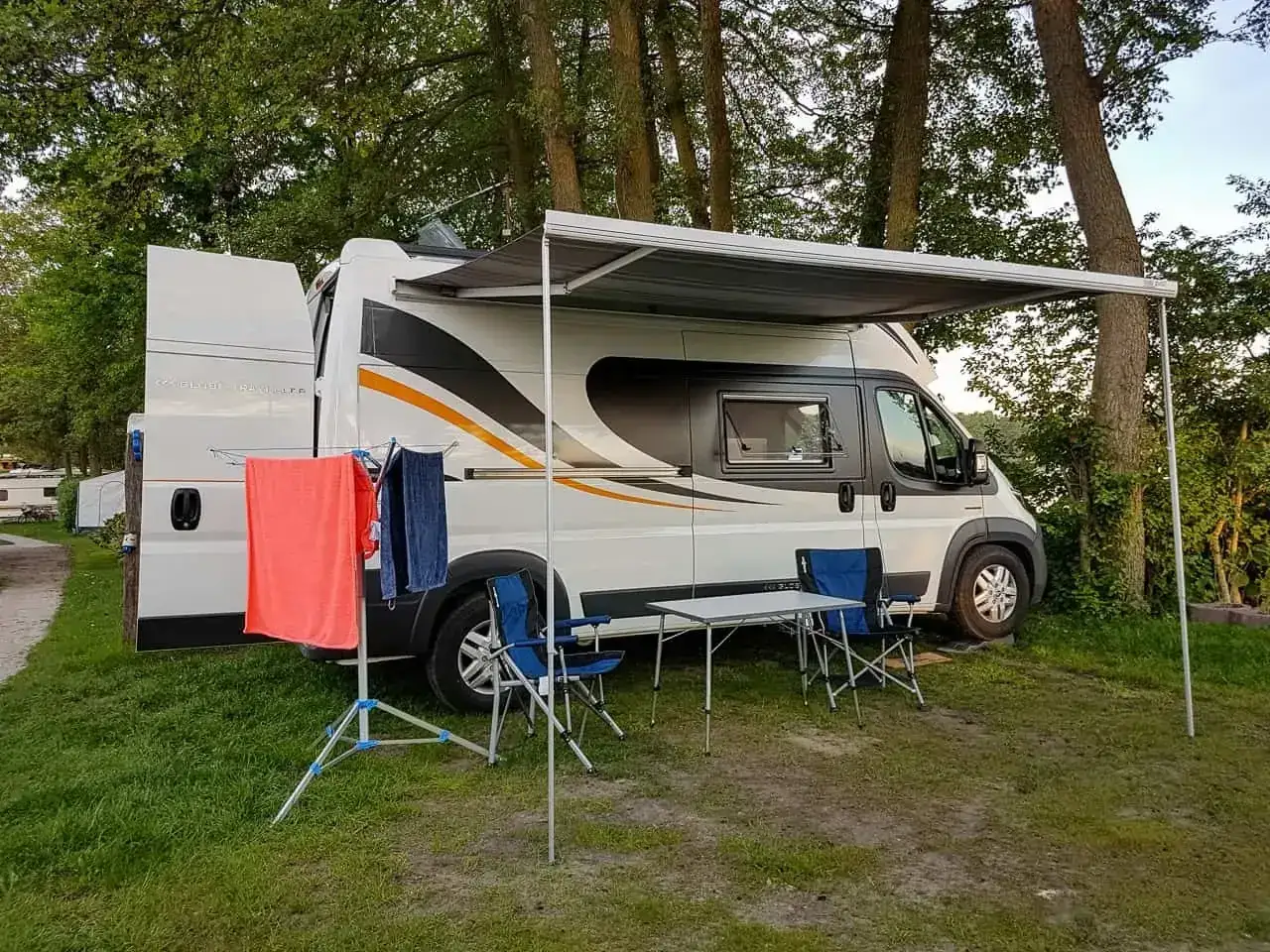 Kamper z rozłożonym markizą, suszarką na pranie i meblami kempingowymi. Praktyczne gadżety do kampera ułatwiające życie na wakacjach.