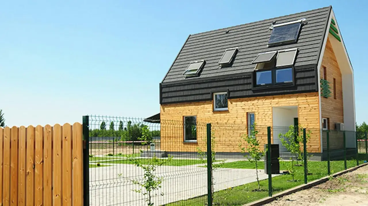 Nowoczesny dom samowystarczalny za 150 tys. z panelami słonecznymi na dachu i drewnianą elewacją.