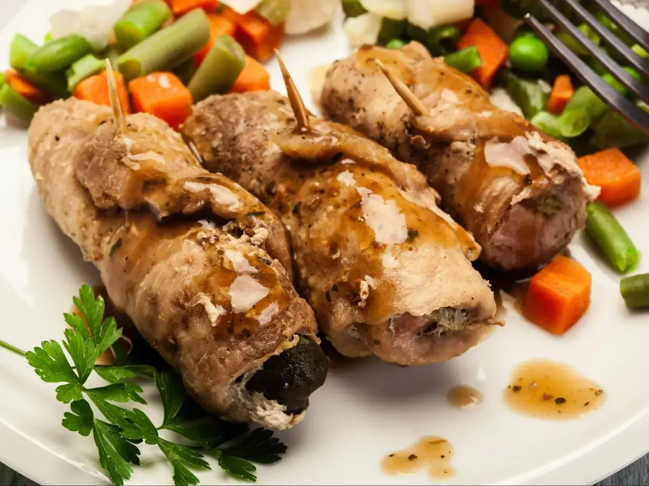 Roladki ze schabu z farszem, polane sosem, podane z warzywami. Idealne pytanie: co zrobić ze schabu na obiad?