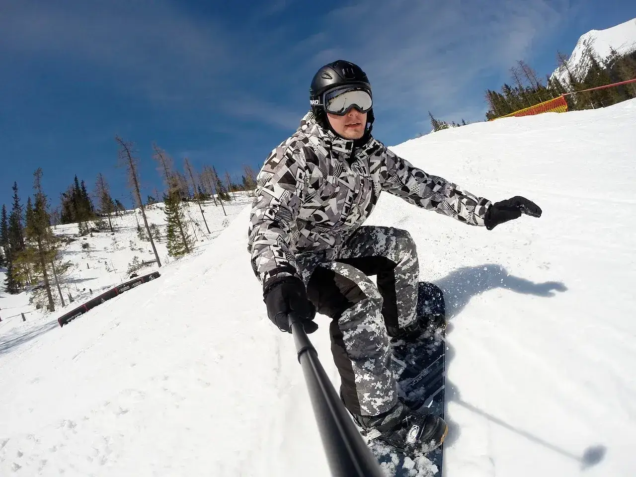 Snowboardzista w kasku i goglach zjeżdża po stoku. Kask narciarski a snowboardowy różnice? Ten kask wygląda na uniwersalny.