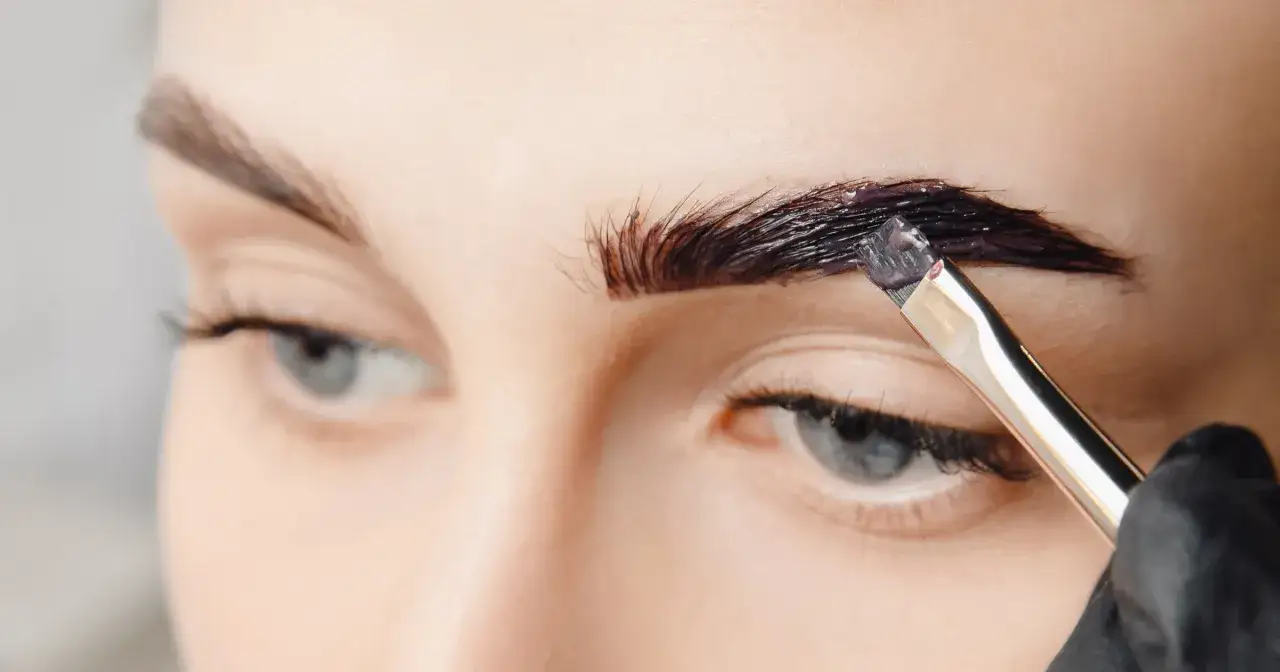 Aplikacja ciemnej henny na brwi pędzlem. Wygląda na to, że to będzie nieudana henna brwi, bo kolor jest zbyt intensywny.