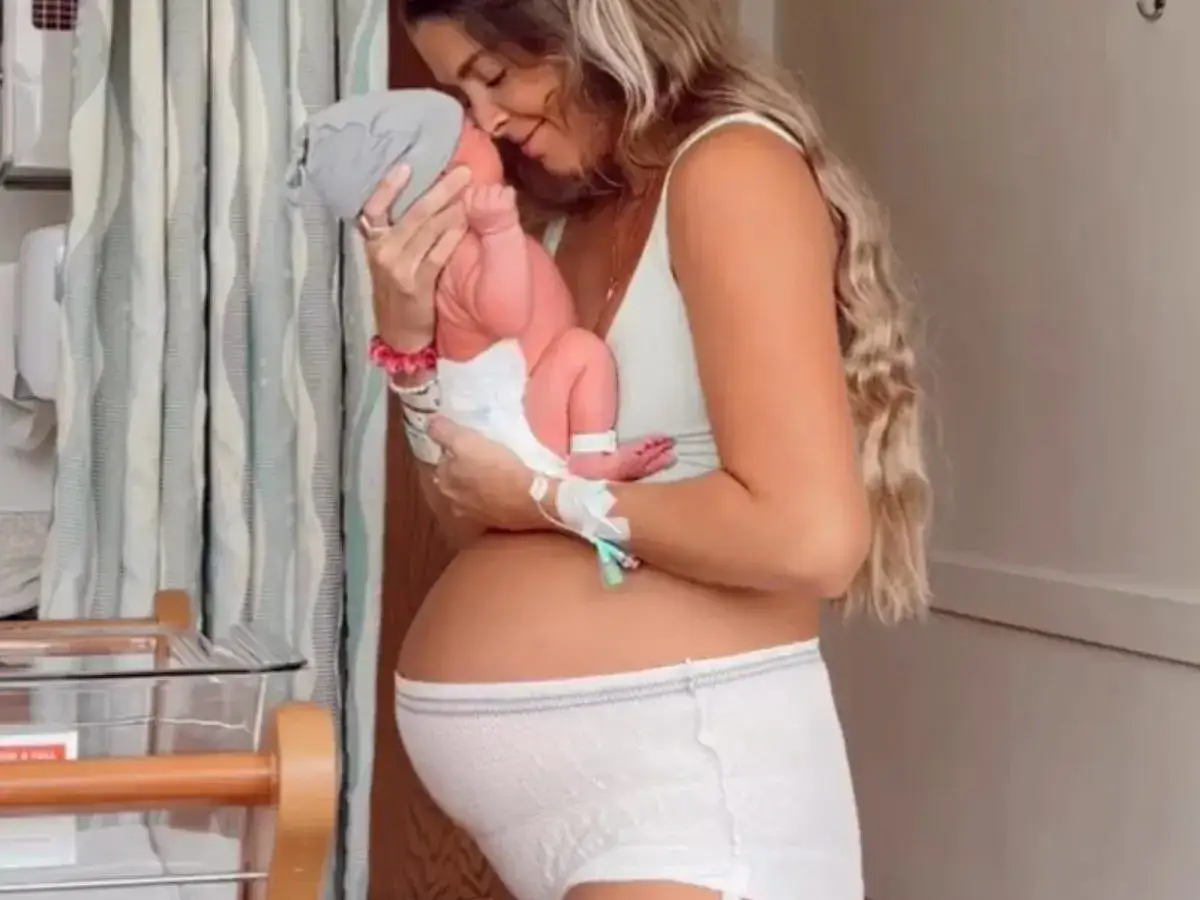 Mama tuli noworodka, czując ulgę po porodzie, mimo bólu brzucha.