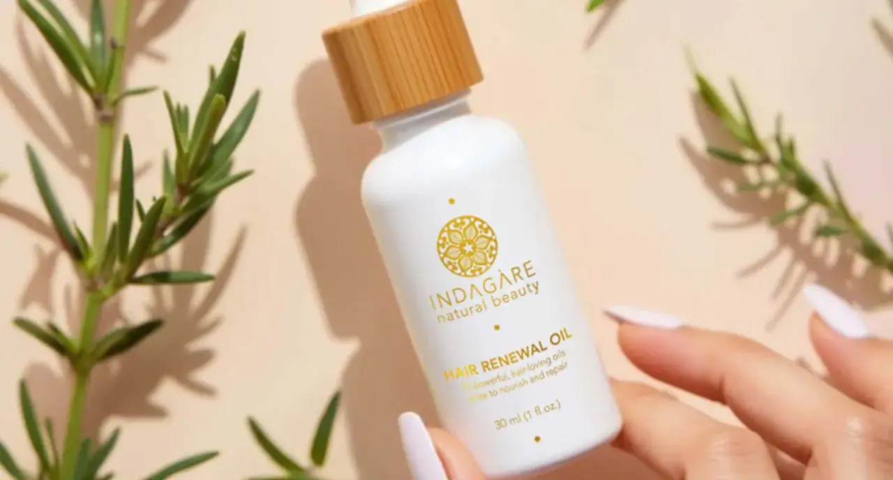 Biała buteleczka z olejkiem do włosów, otoczona gałązkami rozmarynu. Idealny do pielęgnacji włosów.