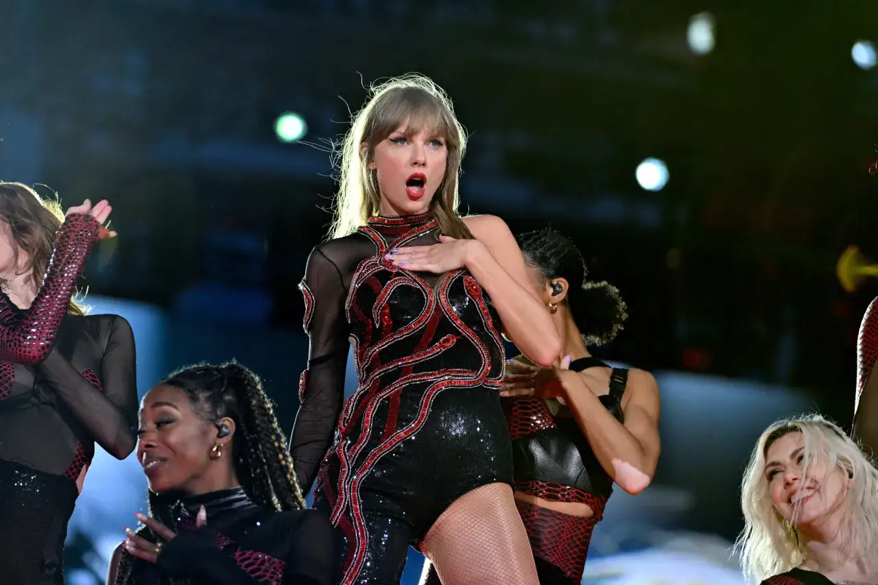 Taylor Swift na scenie w błyszczącym stroju. Fani zastanawiają się, ile lat ma Taylor Swift, gdy widzą jej energię.