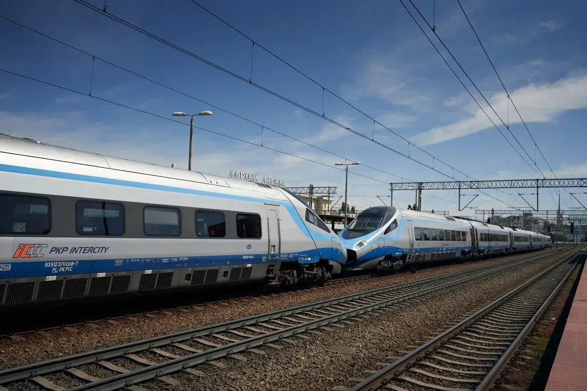 Dwa pociągi PKP Intercity, jeden z Katowic, drugi z Warszawy, stoją obok siebie na torach.