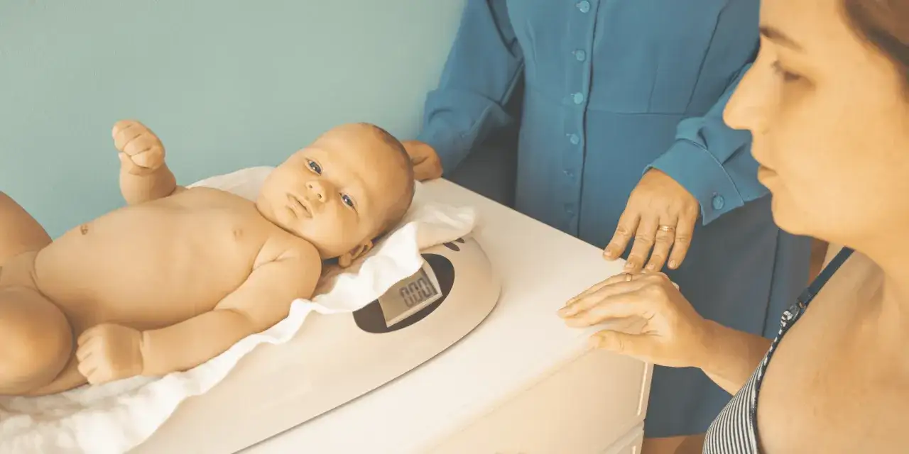 Niemowlę na wadze. Matka i pielęgniarka obserwują, jak rozpoznać brak pokarmu w piersiach, gdy dziecko nie przybiera na wadze.