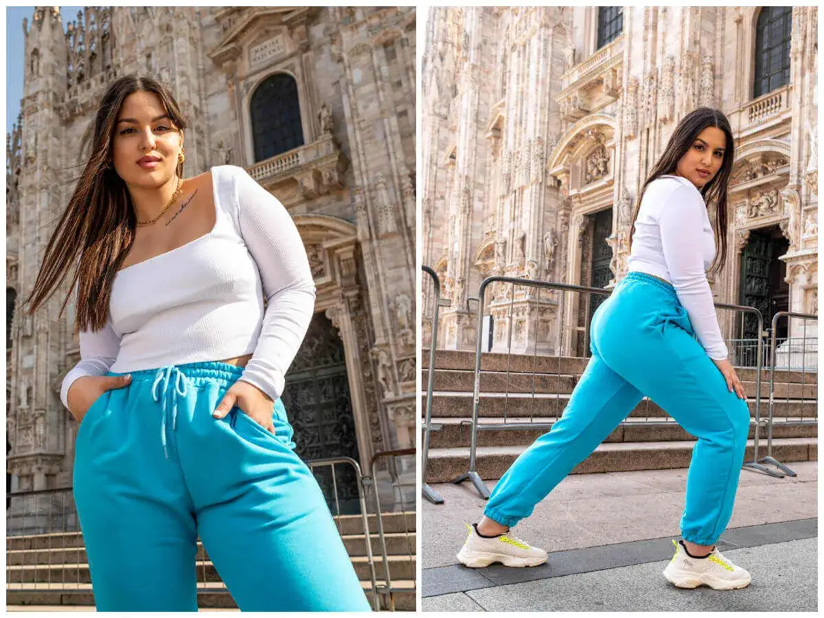 Modelka w turkusowych dresach i białej bluzce damskiej plus size pozuje na tle katedry.