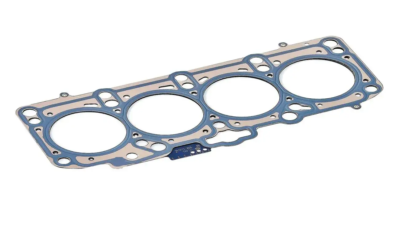 Uszkodzona uszczelka pod głowicą, element silnika z otworami na cylindry i kanały, gotowy do wymiany.