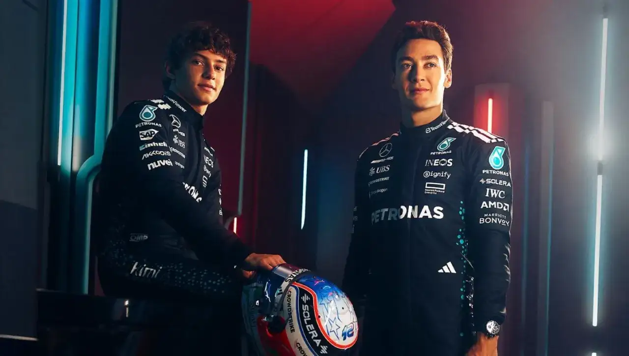 Dw&oacute;ch kierowc&oacute;w zespołu Mercedes-AMG Petronas F1 w kombinezonach, jeden z kaskiem.