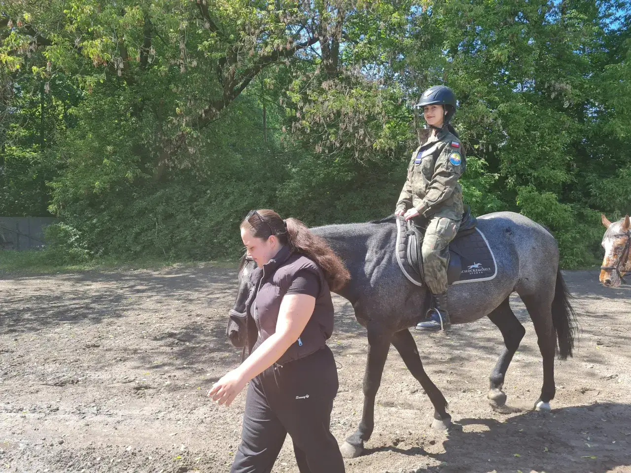 Młoda amazonka w mundurze na koniu, prowadzona przez instruktorkę. Stowarzyszenie Klub Jeździecki Legia Kozielska.