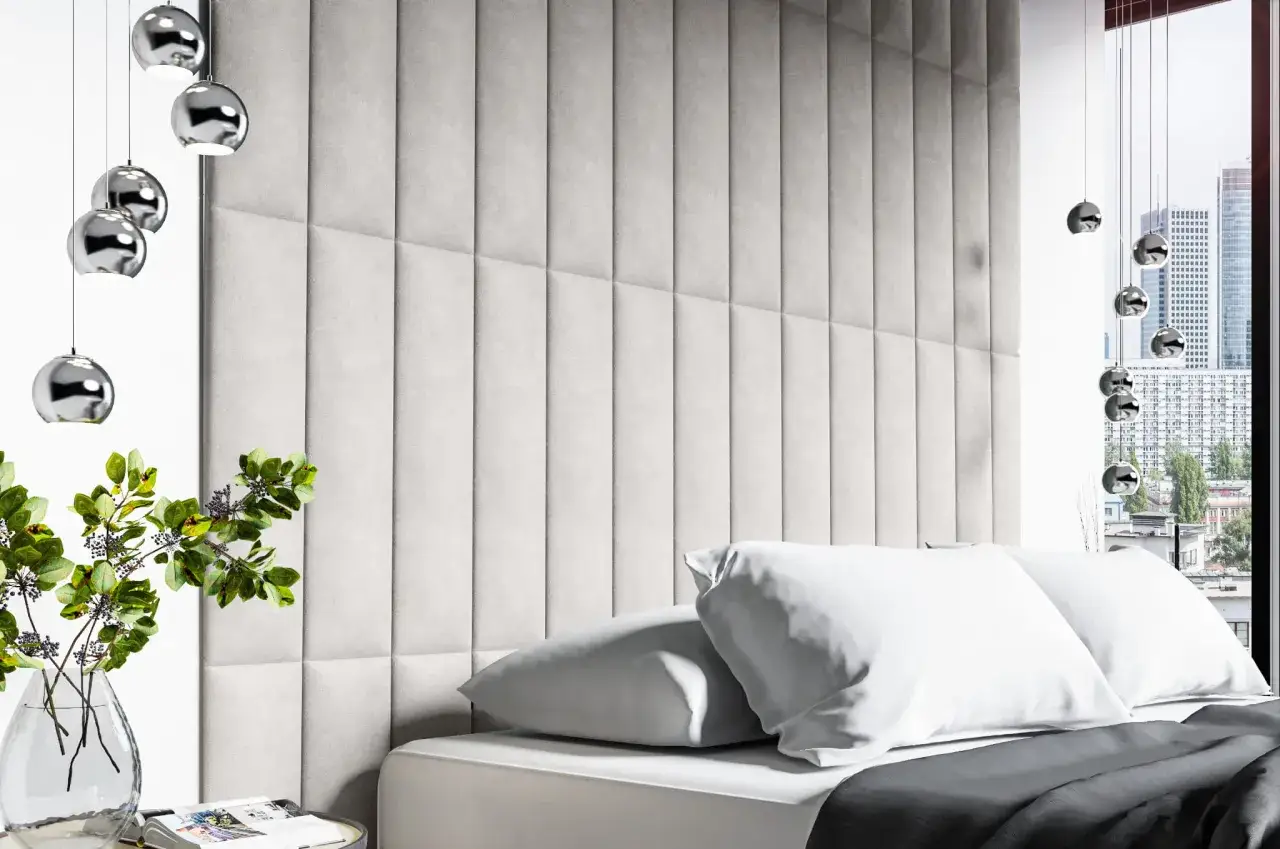 Nowoczesna sypialnia z szarym zagł&oacute;wkiem z paneli tapicerowanych. Czy panele tapicerowane można przykleić na tapetę? Wygodne poduszki i stylowe lampy.