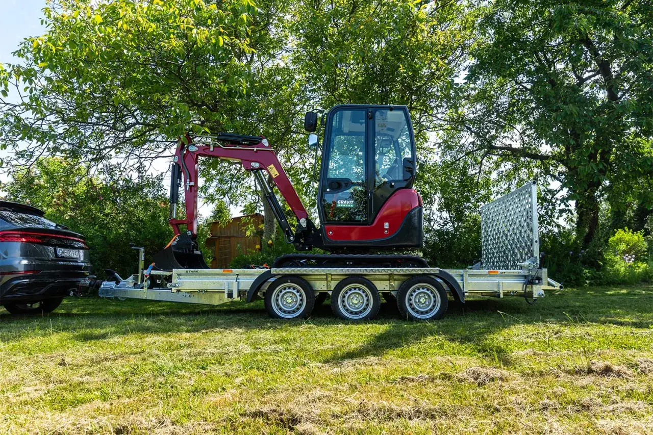 Czerwony minikoparka na przyczepie. Zastanawiasz się, ile waży laweta z takim obciążeniem?