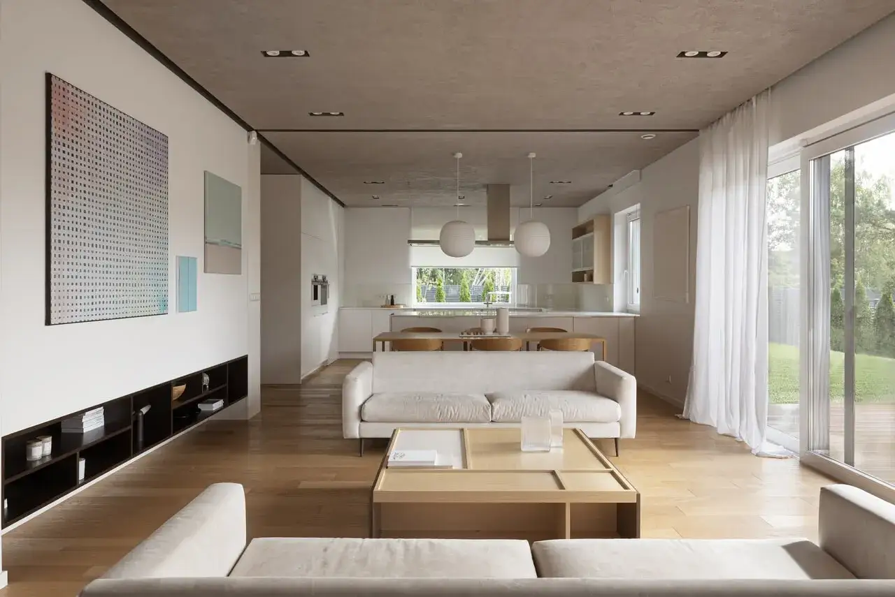 Jasne, przestronne wnętrze z sofami, stołem i kuchnią, gdzie doświetlenie pomieszczeń światłem naturalnym jest kluczowe.